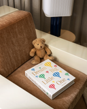 Album fotograficzny "Dream Big Little One" z białą płócienną okładką, złotym napisem i kolorowymi balonami, idealny na zdjęcia z pierwszych lat dziecka.